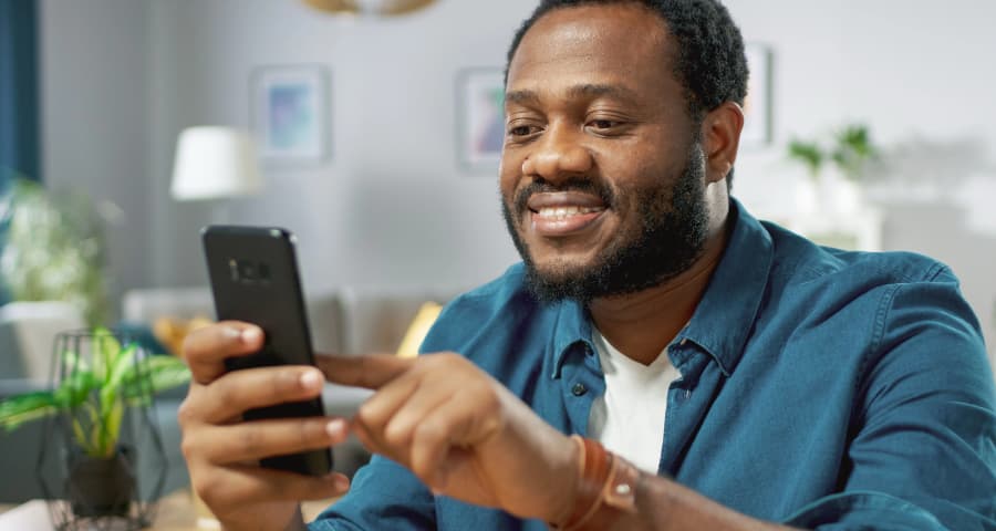Man sitting down navigating a home security app on his cell phone